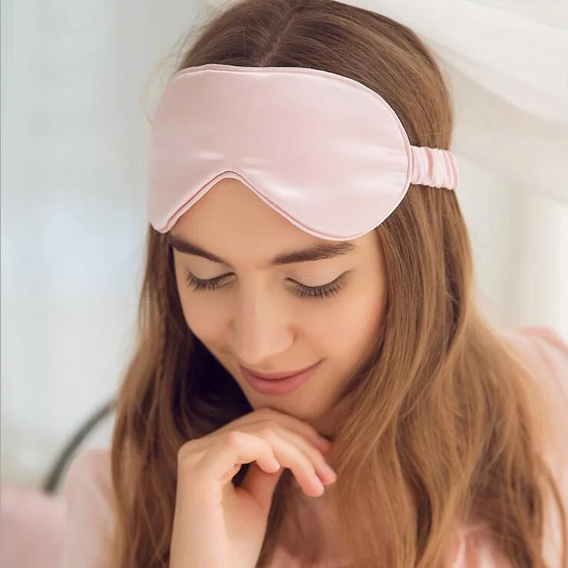 Vrouw met een roze slaapmasker omhoog geschoven op haar voorhoofd